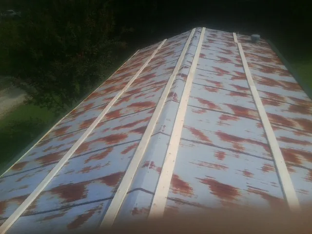 Rusted metal roof panels with new wood purlins before replacement — Storm Damage Roof Repair in Rock Cave by Roofing Brothers