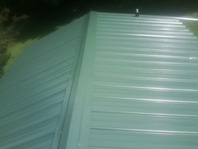 New green metal panels meeting at the ridge of a roof — Flat Roof Repair work by our crew in Rock Cave