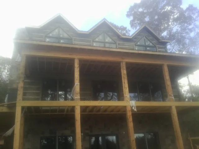 Dormers and porch framing on a large log home under construction — Roof Coating work by our crew in Rock Cave