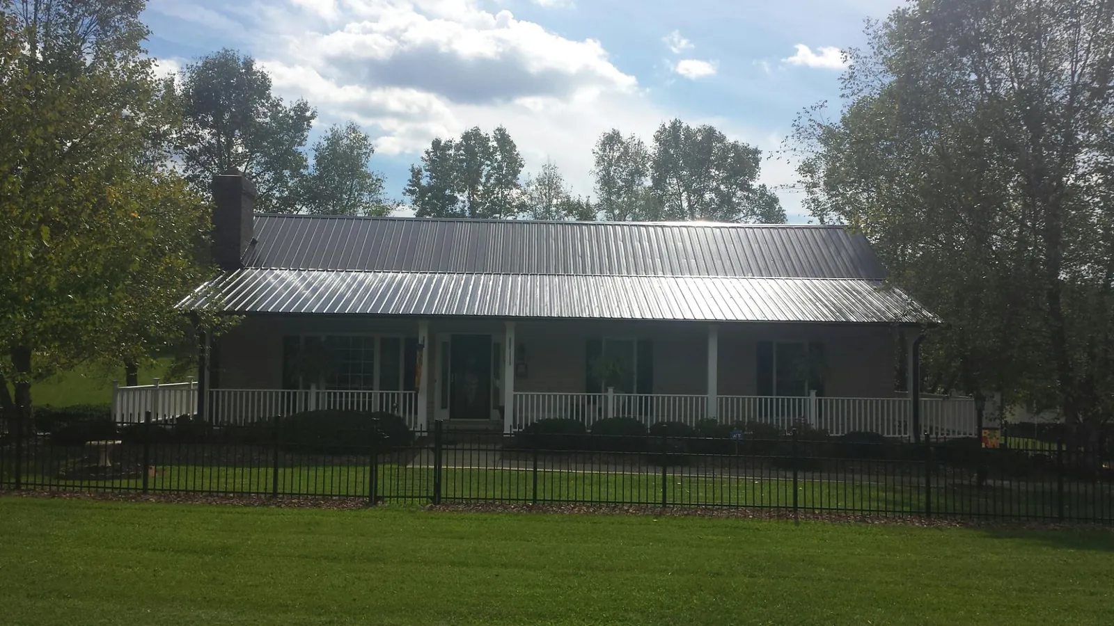 Gray metal roof on a brick ranch with a full width front porch — Gutter Guard Installation work by our crew in Rock Cave