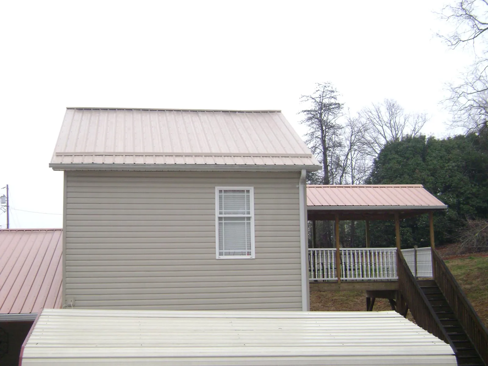 Tan metal roofs on a two story addition and attached porch, from a Roof Replacement job in Rock Cave