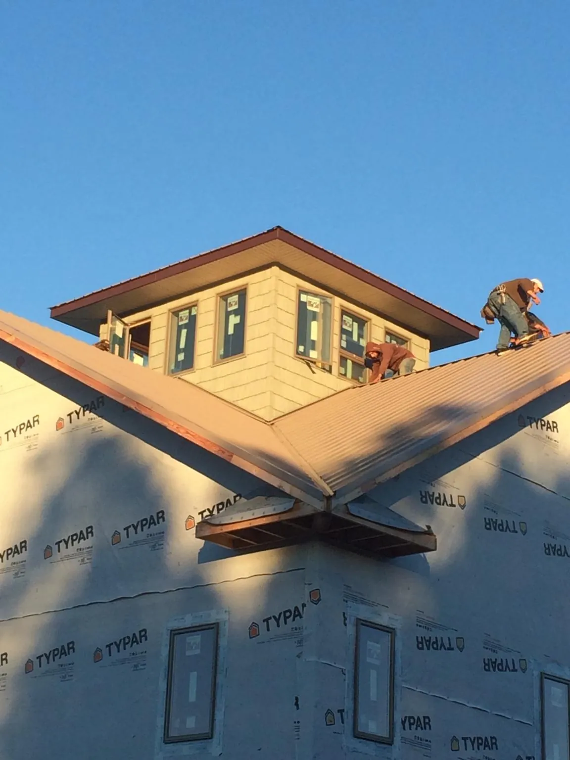 Roofers working around a rooftop cupola on a new metal roof at sunset — Roof Waterproofing in Rock Cave by Roofing Brothers
